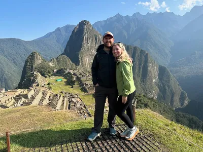 Couple posing happily with Machu Picchu mountains behind.