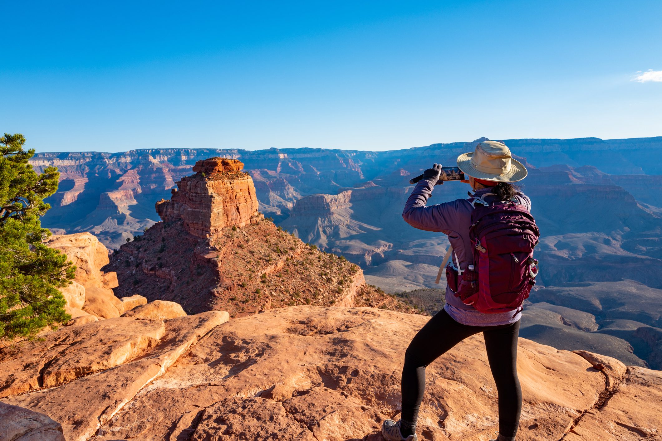 A hiker with a backpack drinking water at a rocky desert viewpoint.