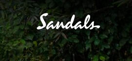 The word 'Sandals' in white script on a dark leafy background.